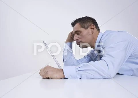 Tired businessman sitting in front of his laptop Stock Photos