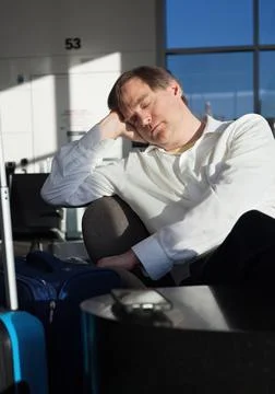 Tired businessman sleeping in airport terminal with luggage Stock Photos