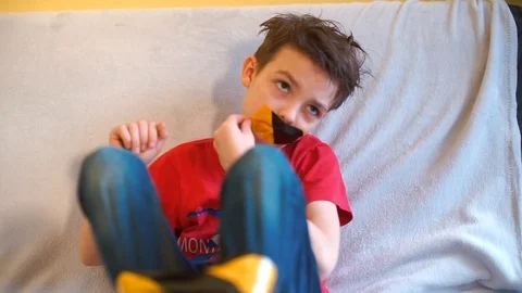 A tired child sitting on the couch opens a masking tape from his mouth Stock Footage 123862378