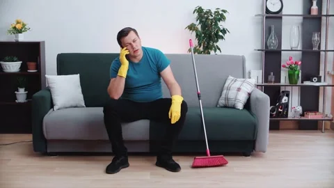 Tired cleaning man sitting on the couch talking on the phone. Stock Footage 145163947
