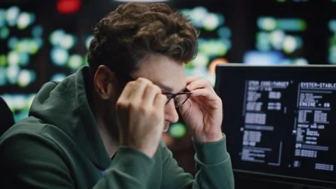 Tired coder working computer at night datacenter closeup. Man wearing glasses Stock Footage 260261717