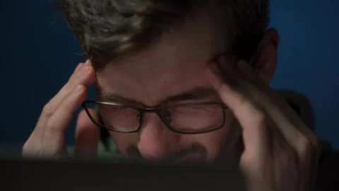 A tired coder working late at night feels a headache and rubs his eyes Stock Footage 303998385