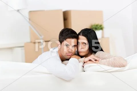 Tired couple sitting on the sofa and looking sad Stock Photos