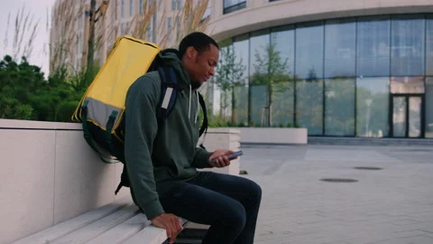 A tired courier sits down on a bench at the end of the working day Stock Footage 222890052