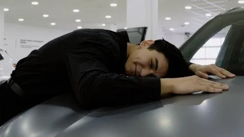 Tired customer lying face down on the hood of a car, Stock-Fotos