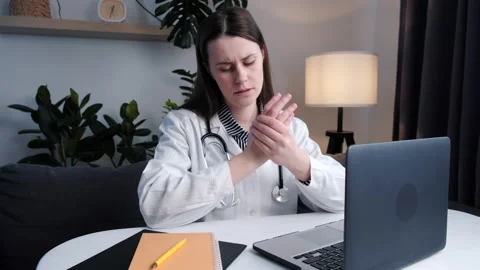 Tired doctor at computer experiences pain and discomfort in hands Stock Footage 235153807