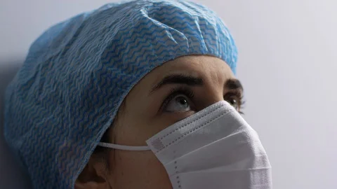 Tired doctor or nurse in face mask taking hat off Stock Footage