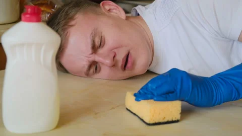 Tired doomed funny man cleans the surface with a sponge and detergent. Stock-Footage 125571403
