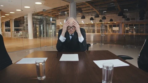 Tired elderly businessman sitting alone in conference room Stock Footage 126211995