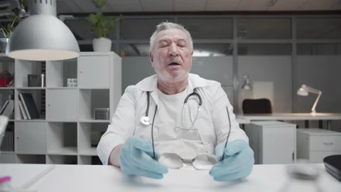 A tired elderly experienced doctor has finished his day at the workplace in the Stock Footage 152342915