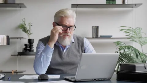 Tired elderly man sit at desk take off glasses rest from laptop reduces Stock Footage 142751440