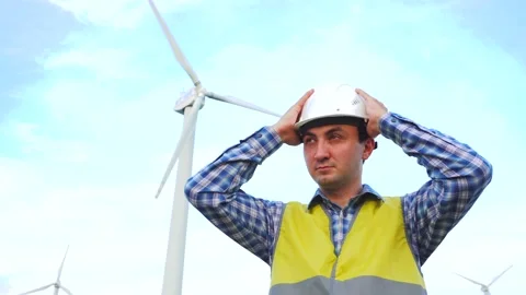 Tired engineer at minute at rest in front of wind turbines ecological energy Stock Footage 137969311