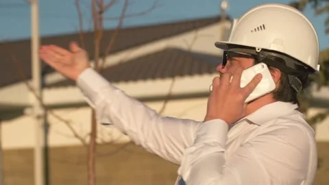 Tired engineer talking on phone, solving problems standing at construction site Stock Footage 269476770