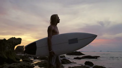 Tired exhausted man after training on surfboard looks at setting sun. Tired but Stock Footage 243818652