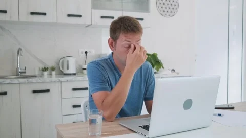 Tired exhausted man freelancer working at home on laptop, overworked, needs rest Stock Footage 250115804