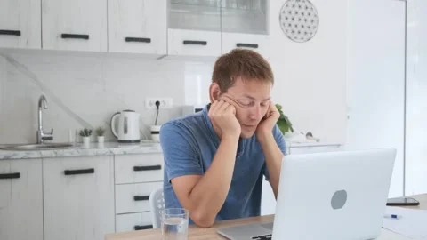 Tired exhausted man freelancer working at home on laptop, overworked, needs rest Stock Footage 252117577