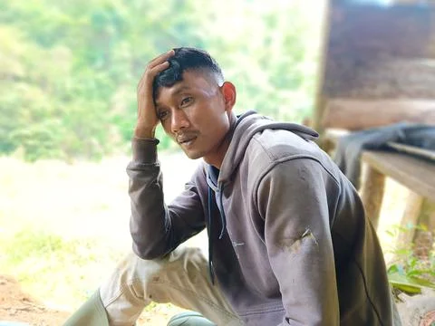 A tired farmer takes a break while holding his head. Stock Photos