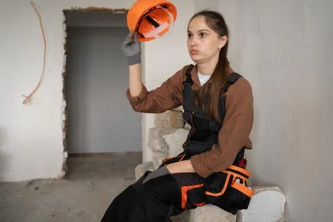 Tired female builder taking off her helmet with a displeased expression. Stock Photos
