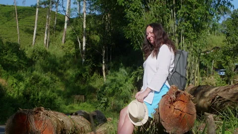 Tired female explorer relaxing while looking at forest on sunny day 動画素材 251670960