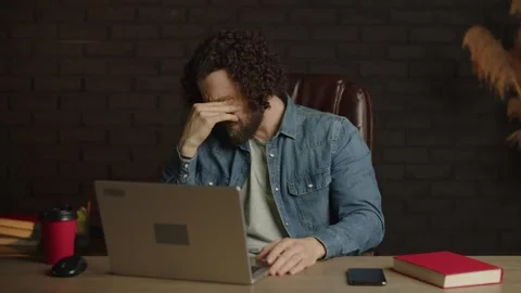 Tired freelancer with a beard at the workplace in the office is unhappy Stock Footage 249892966