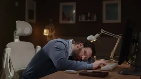 Tired freelancer. Exhausted remote worker sleeps at his computer desk Видео 337645548