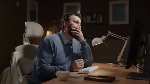 Tired freelancer. Tired remote worker at computer sighs, rubs his eyes, and Видео 337643321