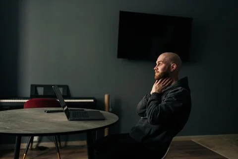 Tired freelancer touching neck while sitting at home office desk with laptop 스톡 사진