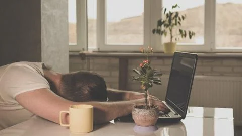 Tired guy fell asleep at the table,working at home. Stock Photos