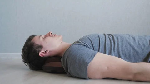 Tired guy is lying on the floor with electric massage pillow. Stock Footage 107177800