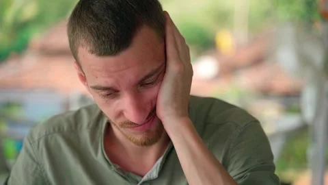 A tired guy nervously strokes his head, looking at the camera. Close-up. Video stock 231336466