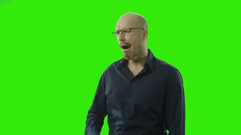 Tired guy taking of his glasses and yawns a lot in front of a green screen Stock Footage 166511227