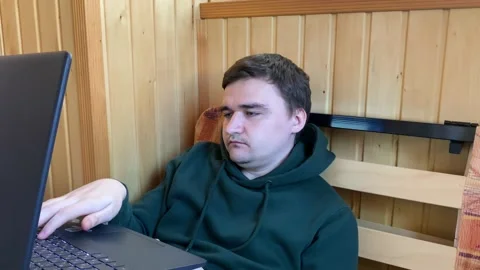 Tired guy yawning and falling asleep while doing boring work tasks on laptop Vidéo 194177567