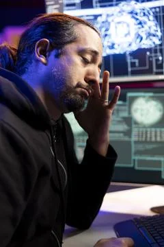 Tired hacker rubbing eyes while stealing sensitive information using VPN Stock Photos