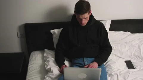 Tired handsome caucasian man using laptop on bed late at night before falling Stock Footage 148385302