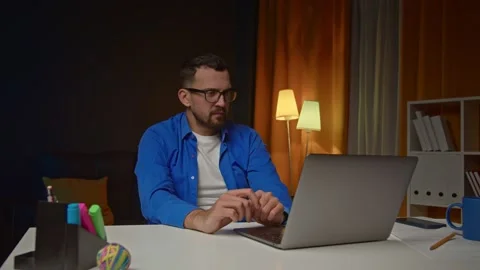Tired handsome man drinking coffee and looking on computer screen in home office Stock Footage 171578826