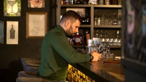 Tired hipster drinks whiskey in a bar and texts Stock Footage 126030516