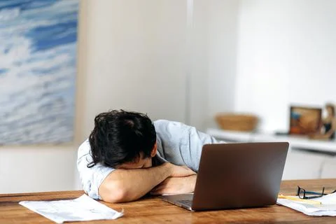 Tired hispanic guy, manager, freelancer or student working or studying using Stock Photos