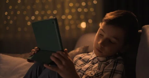 Tired kid boy falling asleep with tablet gadjet in hands sitting on sofa Stock Footage 249289556