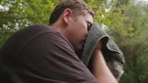 Tired man after marathon run wipes sweat from his face with a towel, promoting Stock Footage 303552258