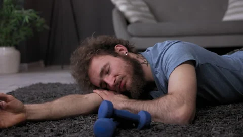Tired man after sport on floor. Sportsman on carpet. young stylish fashionable Stock Footage 159215744
