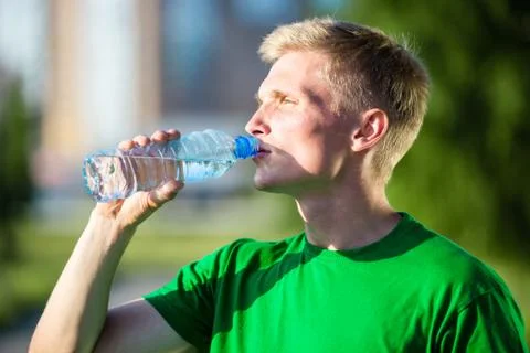 Tired man drinking water from a plastic bottle after fitness Stock Photos
