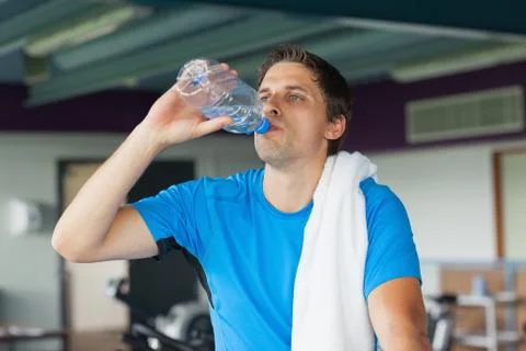 Tired man drinking water while working out in gym Fotos Stock