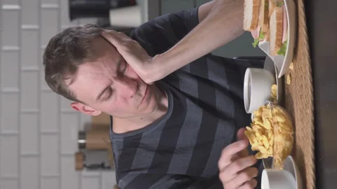 Tired man eating in the kitchen Stock Footage 227760884