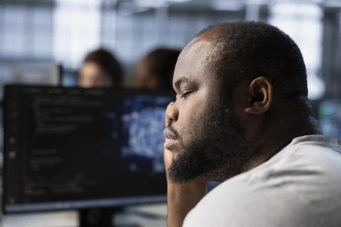 Tired man falling asleep while using AI technology in data center Stockfoto's