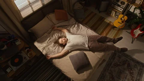 Tired Man Falling Onto Bed to Rest after Work in Home Studio Stock Footage 337500321