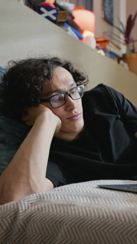 Tired Man with Glasses Lying down and Working on Laptop Stock Footage 338421478