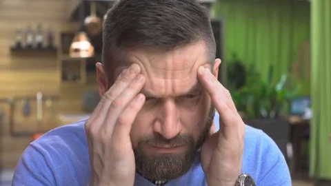 Tired man has a headache, portrait, in pub, cafe, close steadicam shot 動画素材 73067246