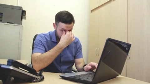 Tired man with laptop computer rubbing eyes at office Stock Footage 84492878