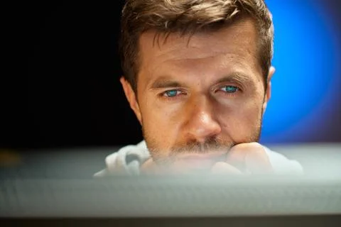 Tired man looking at computer screen at night 写真素材