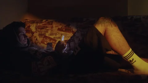Tired man lying on couch and using smartphone at night Vídeo Stock 327785200